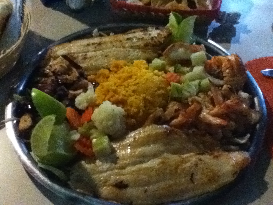 A plate full of fish, rice, and other foods.