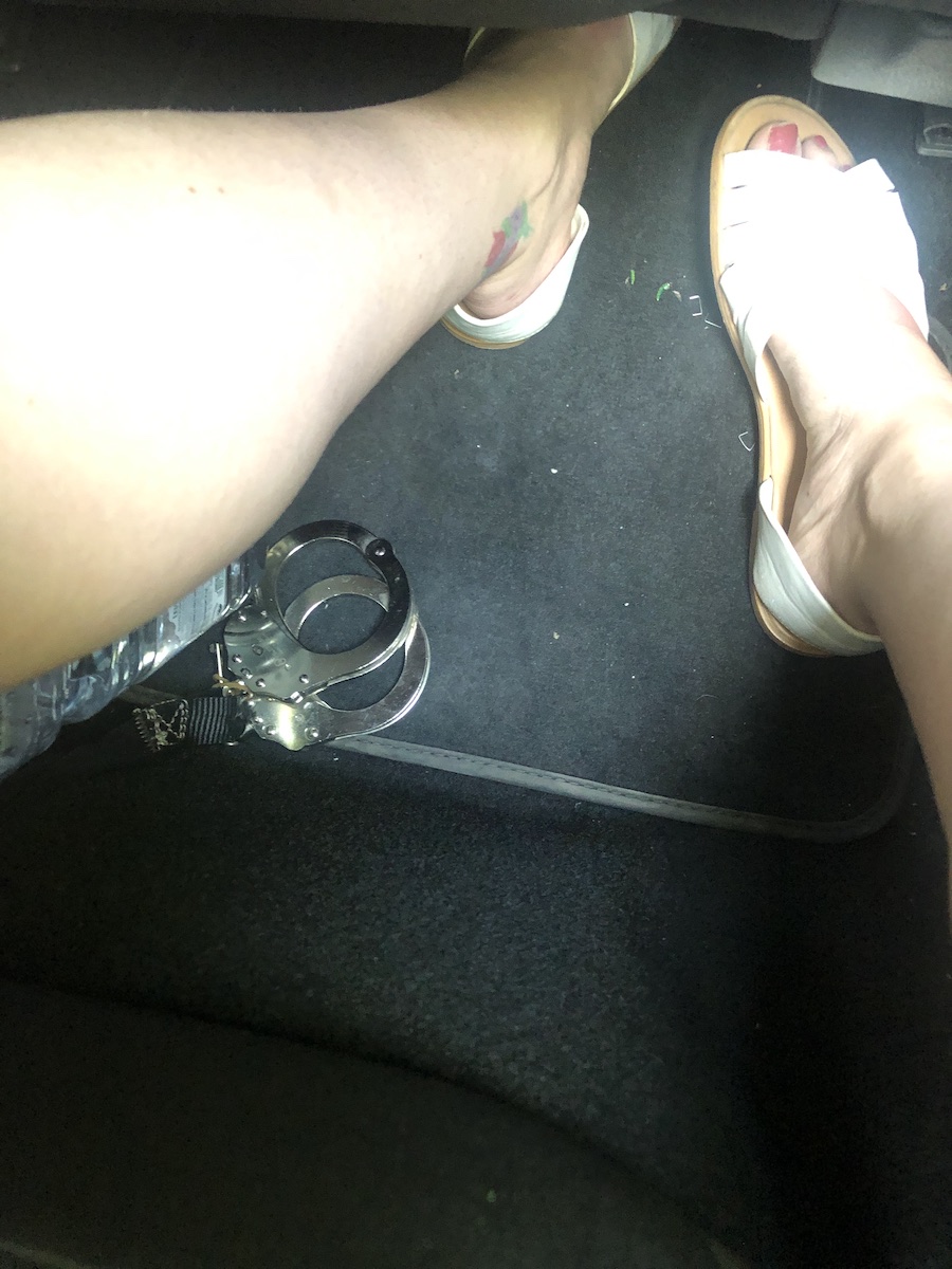 My legs and feet in the back of a police car with handcuffs in view on the floor