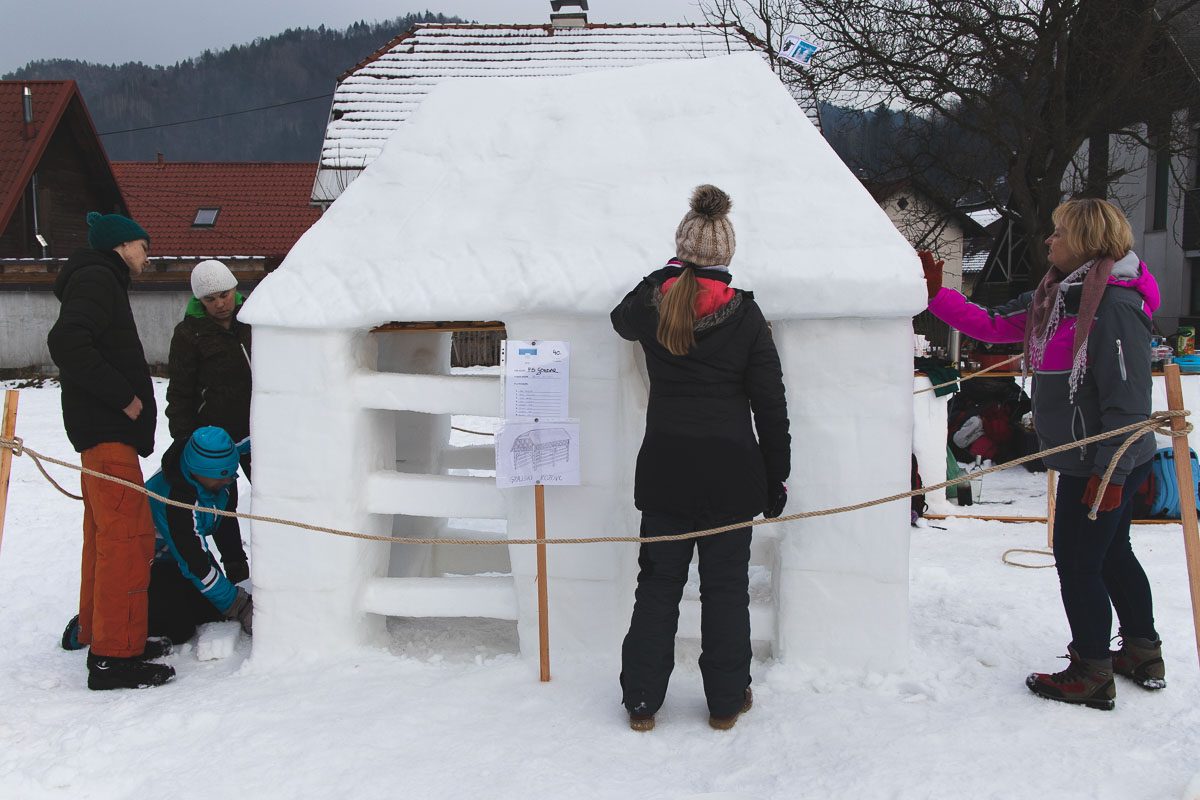 people building a snow kozolec (hayrack)