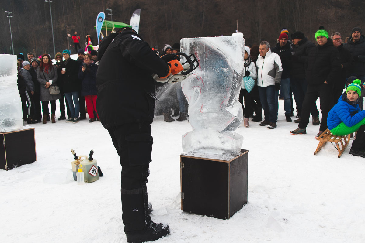 man carving ice sculpture with chainsaw